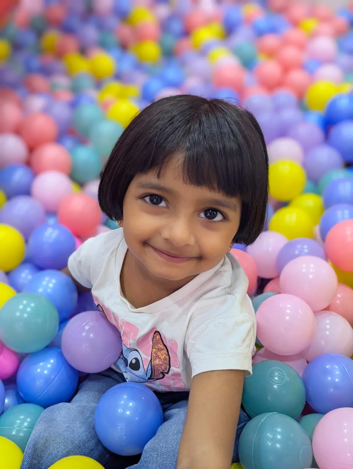 Child sitting in the colourful ball pit at Lollipop Locs