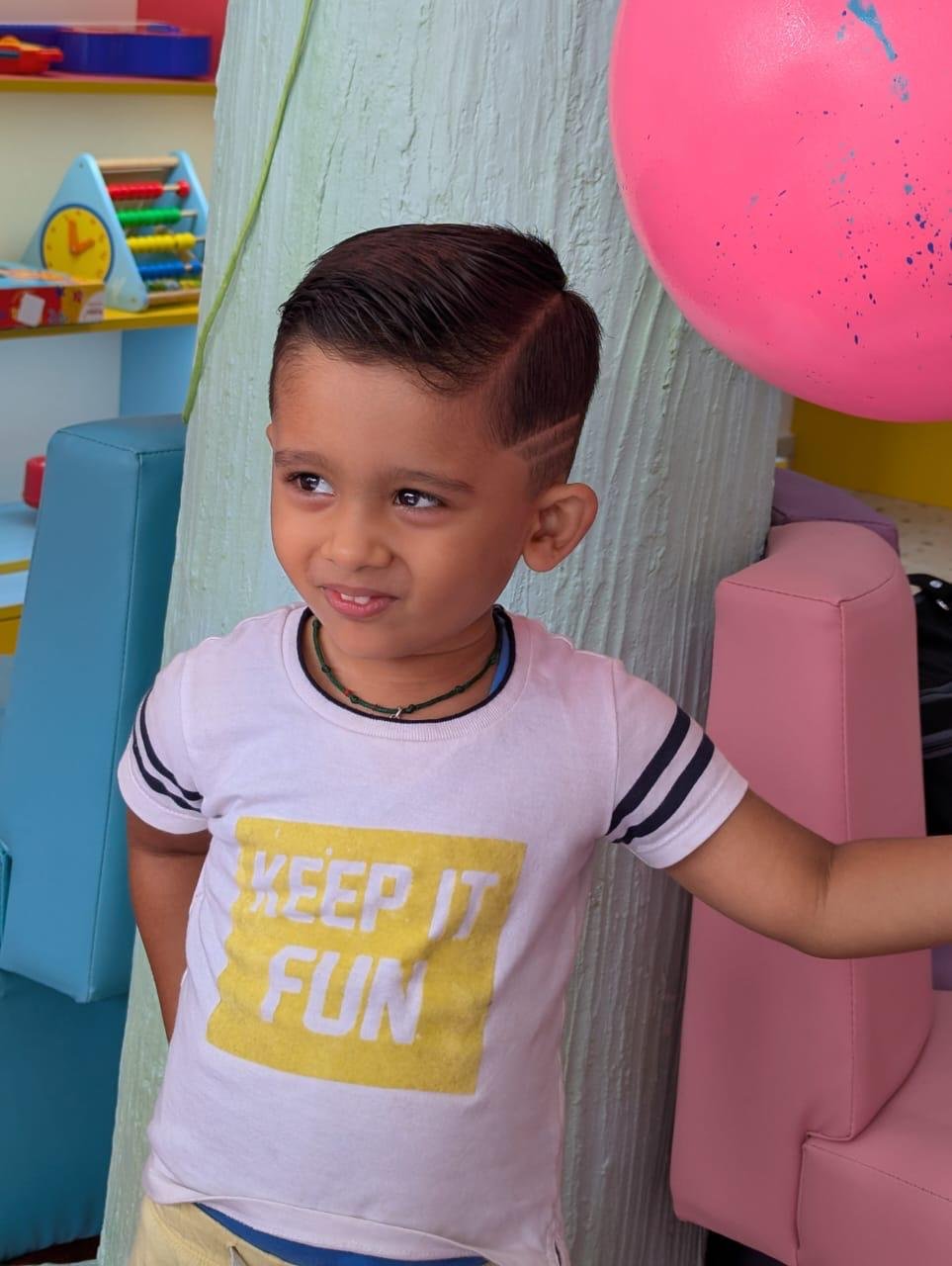 Boy showing off a fresh haircut with shaved side-line design at Lollipop Locs