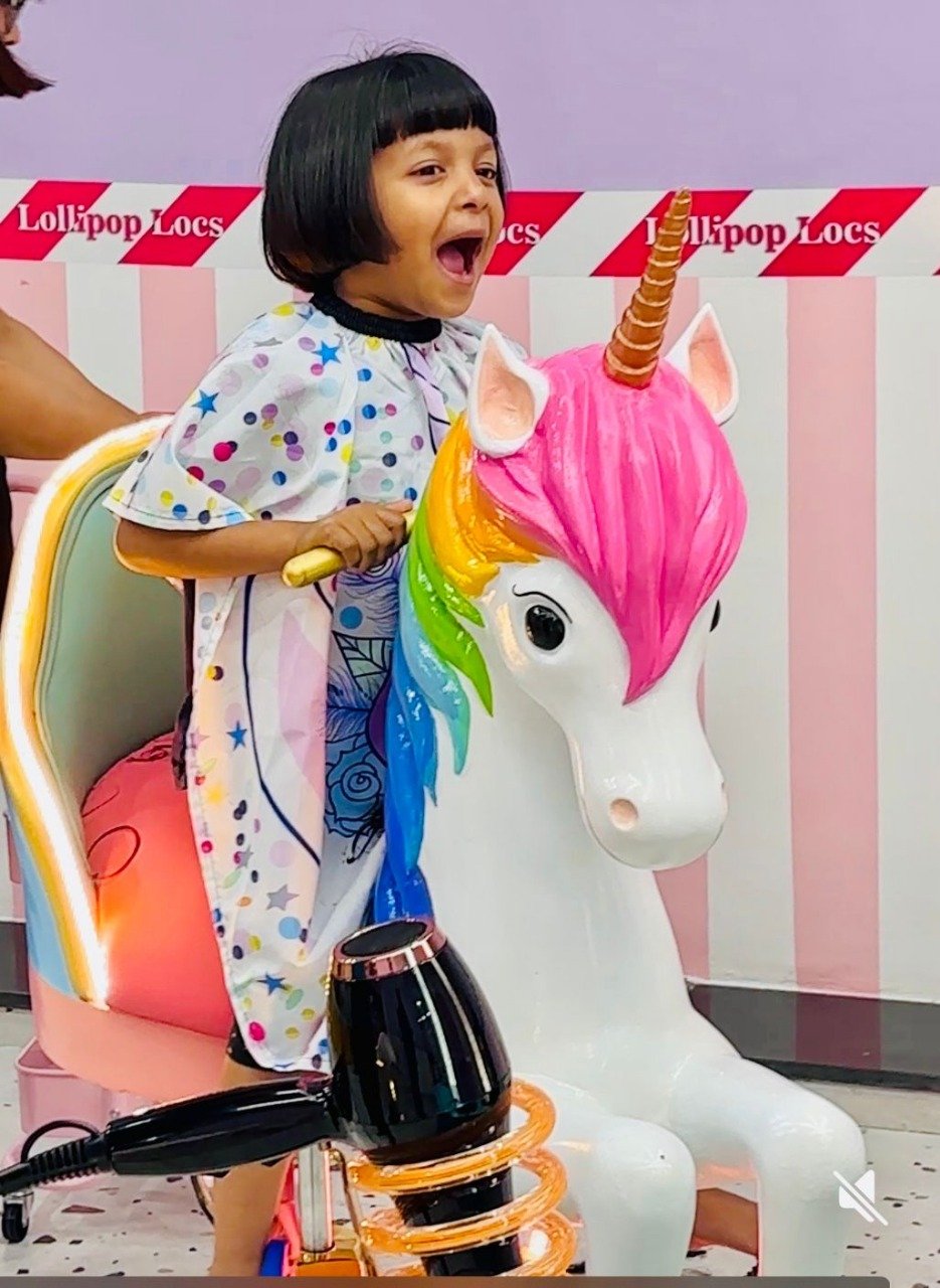 Girl getting a haircut in the unicorn-themed chair at Lollipop Locs